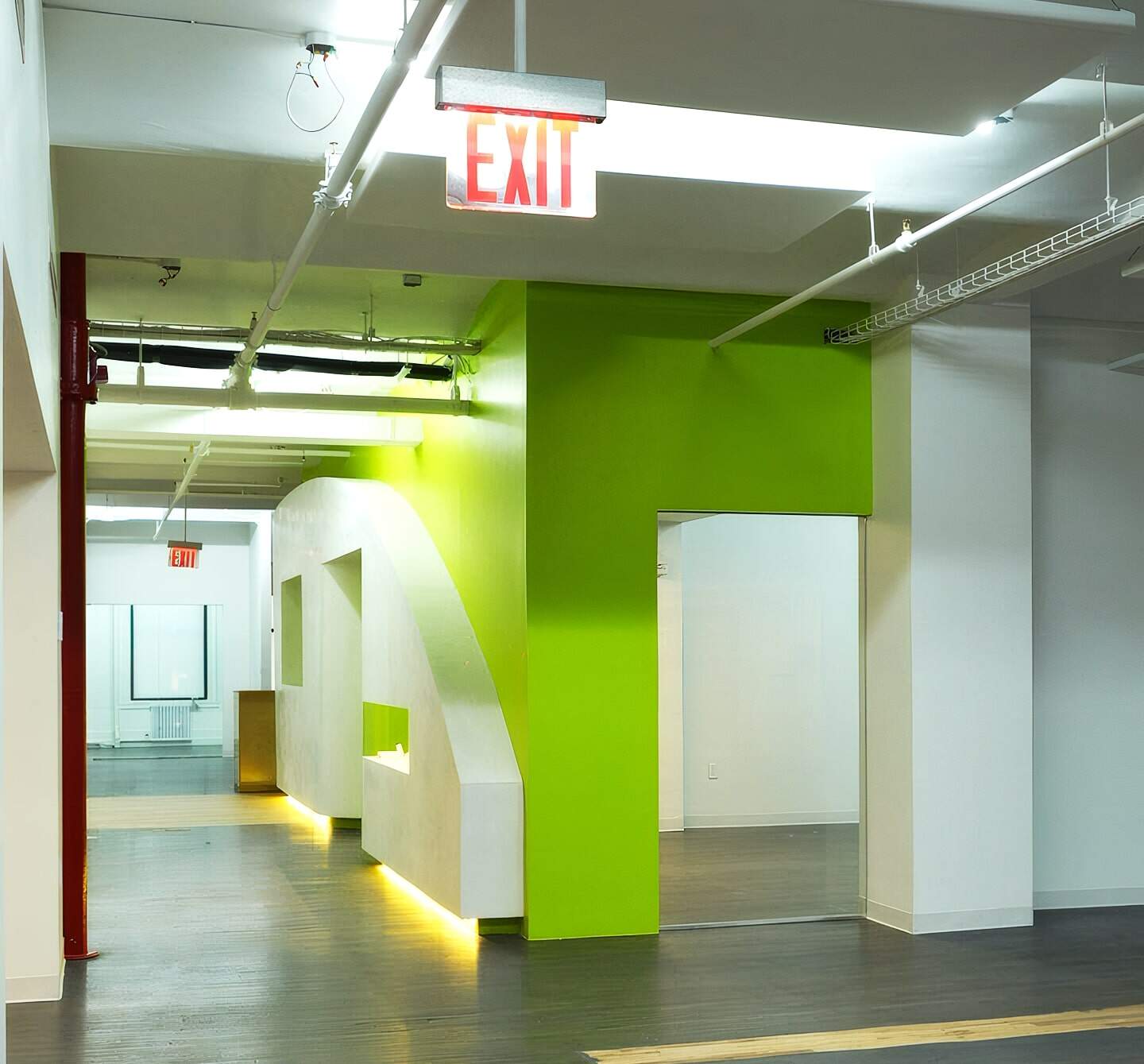 Modern Commercial Interior With Vibrant Green Accent Wall, Clean White Surfaces, And Polished Wooden Flooring, Illustrating Professional Building Renovations By American Builders.