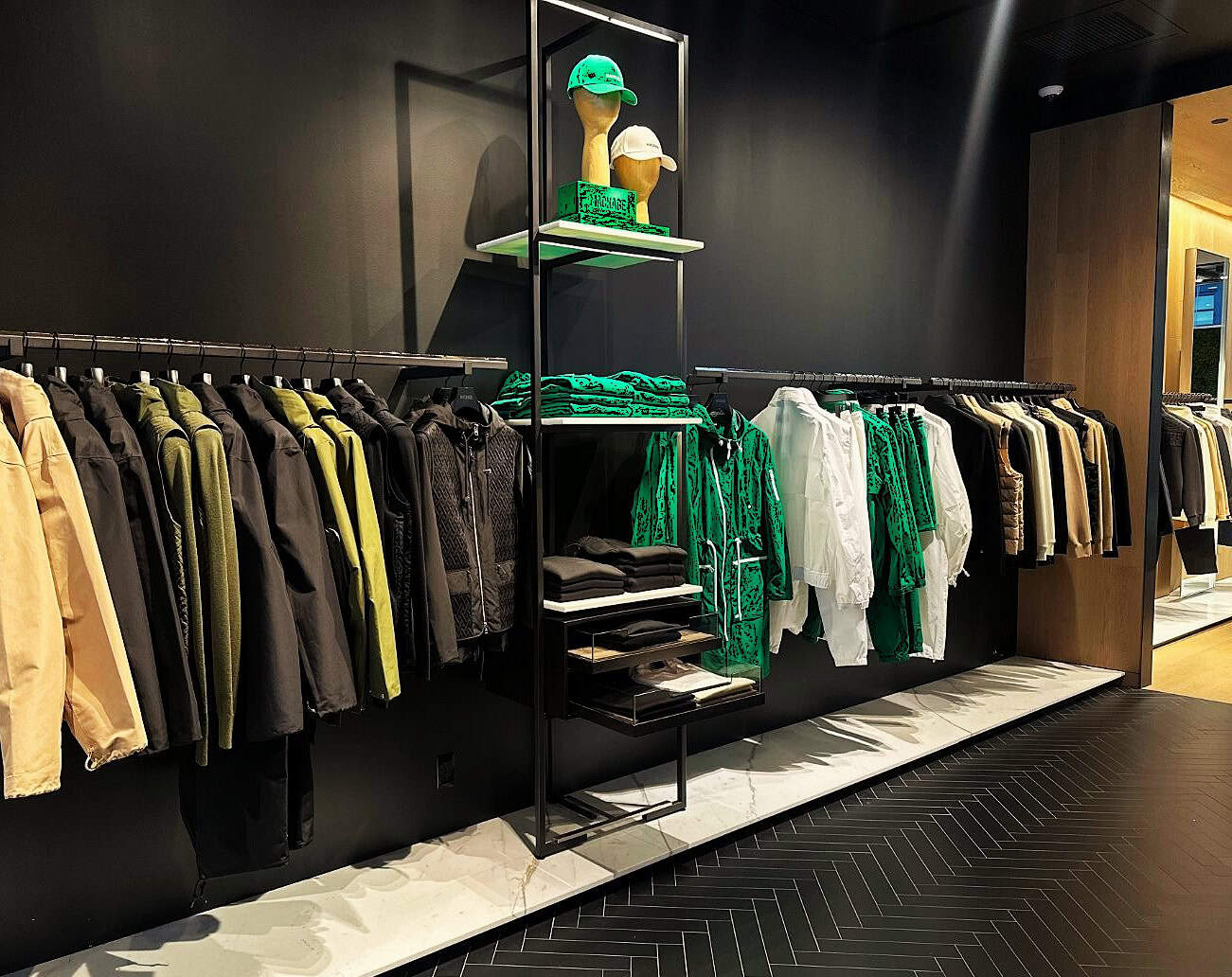 Jackets And Apparel Display In A Modern Retail Clothing Store, Showcasing Outdoor And Athletic Wear For Customers, With Stylish Shelving And A Sleek Design.